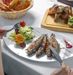 Poster - woman eating grilled fish with lettuce, grilled lemon and tomato