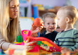 © Oksana Kuzmina - Children toddlers and nursery teacher play with toy scales in kindergarten playroom