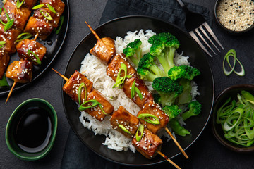 Wall Mural - Teriyaki salmon skewers with rice and broccoli on black plate