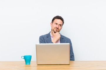 young handsome businessman thinking, feeling doubtful and confused, with different options, wondering which decision to make