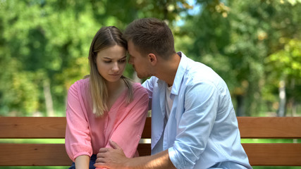 Wall Mural - Young male supporting sad girlfriend sitting park bench together, loving spouse