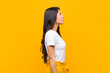 © kues1 - young pretty latin woman on profile view looking to copy space ahead, thinking, imagining or daydreaming against orange wall