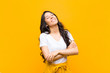 young pretty latin woman laughing happily with arms crossed, with a relaxed, positive and satisfied pose against orange wall