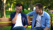 Man comforting sad male friend sitting on bench in park, life problems, support