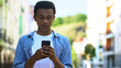 © motortion - Afro-American male teenager chatting smartphone outdoors, online communication