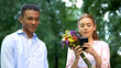 Gadget addicted girl with flowers chatting on smartphone ignoring boyfriend