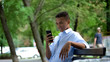 © motortion - African american guy chatting on smartphone spending time on bench in park