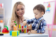 © Oksana Kuzmina - Cute baby playing with toys with teacher or mother indoors