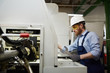 © AnnaStills - Young bearded repairman in protective workwear using wrench and working on lathe in the plant
