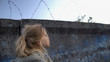 © motortion - Little refugee girl looking at barbed wire, dreaming of new homeland, migration