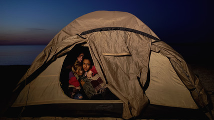 refugee family sitting in tent, hiding from migration border service on shore
