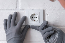 The Guy Installs New Sockets. Repair In The House. The Guy Twists The Screws On The Sockets With A Screwdriver. Rosette On A White Loft Background.
