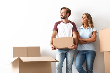 Wall Mural - Photo of smiling couple looking aside and holding cardboard box