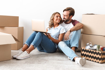 Canvas Print - Photo of pleased couple using laptop and hugging while sitting