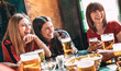 Happy women best friends drinking beer at vintage bar restaurant - Female friendship concept with young girlfriends enjoying time and having genuine fun together at brewery pub - Natural light filter