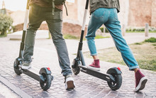 Close Up Of People Couple Using Electric Scooter In City Park - Millenial Students Riding New Modern Ecological Mean Of Transport - Green Eco Energy Concept With Zero Emission - Warm Sunshine Filter