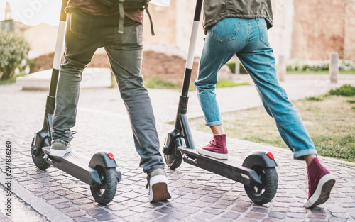 Fotomural Close up of people couple using electric scooter in city park - Millenial studen
