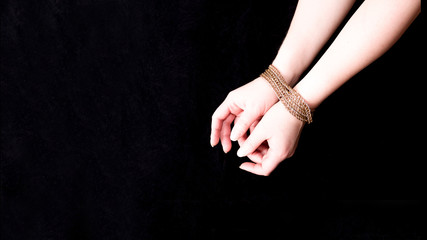 female hands tied with a golden chain, life in a golden cage, eastern wife, black background