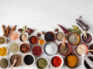 Wall Mural - Various dry spices flat lay in small bowls on white wood background. Top view, copy space