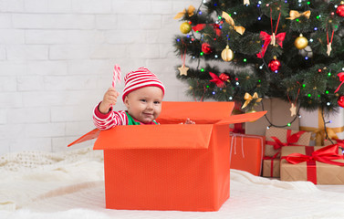 Wall Mural - Cheerful baby with lollipop sitting in big present box