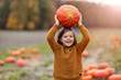 © pikselstock - Boy standing on pumpkin in pumpkin patch