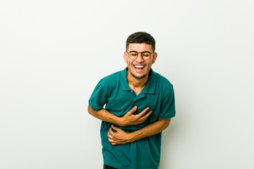 Wall Mural - Young hispanic man laughs happily and has fun keeping hands on stomach.