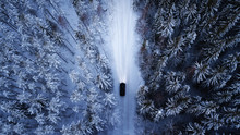 Aerial View Of A Car On Winter Road In The Forest.  Aerial Photography Of Snowy Forest With Car On The Road.  Aerial Photo. Car In Motion