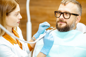 Wall Mural - Female dentist and handsome man as a patient during a medical consultation at the dental office