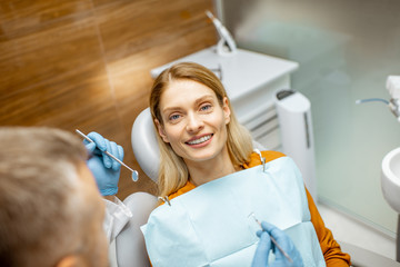 Wall Mural - Beautiful woman as a patient during a teeth inspection with a senior experienced dentist at the clinic