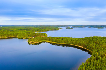 Canvas Print - Aerial view of road between green summer forest and blue lake in Finland. Saimaa lake, Puumala.