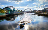 A boat sailing down the River Tyne as it approaches the Millennium Bridge with the Gateshead Sage, Newcastle Crown Court and Newcastle Tyne Bridge in the distance.
