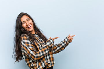 Wall Mural - Young cool indian woman excited pointing with forefingers away.