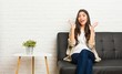 © Asier - Young arab woman sitting on the sofa celebrating a victory or success, he is surprised and shocked.