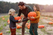 © pikselstock - Father and sons in pumpkin patch field