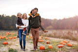 Happy young family in pumpkin patch field