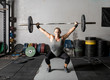 Front view of strong young woman lifting weights over her head