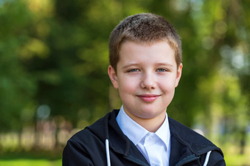 Portrait of smiling 10 year old boy. Happy, chubby boy, outdoors in a park.