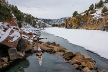 Young Woman In Bikini Lies In Radium Hot Springs And Observes Snowy Landscape