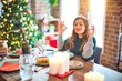© Krakenimages.com - Young beautiful woman sitting eating food around christmas tree at home relax and smiling with eyes closed doing meditation gesture with fingers. Yoga concept.