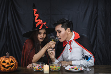 Couple in costume celebrate Halloween party black cloth background.