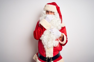 Wall Mural - Middle age handsome man wearing Santa costume standing over isolated white background smelling something stinky and disgusting, intolerable smell, holding breath with fingers on nose. Bad smells 