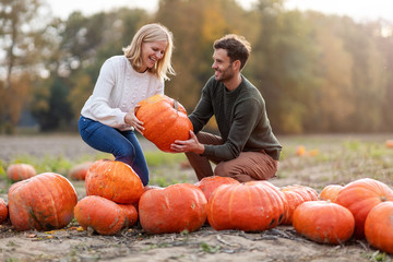 happy young couple in pumpkin patch field