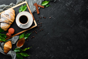 Breakfast. Coffee, croissant and macaroons. On a black stone background. Top view. Free space for your text.