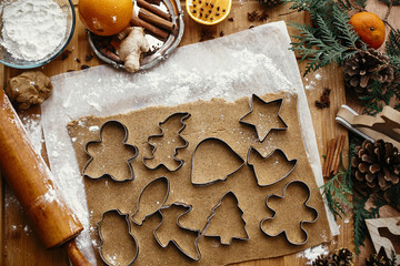 Wall Mural - Making christmas gingerbread cookies, flat lay. Raw dough with metal cutters for cookies and wooden rolling pin, anise, ginger, cinnamon, pine cones, fir branches on rustic table.