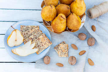 Poster - Ripe juicy autumn pears with cookies and nuts on a white wooden background and a cloth in rustic style top view