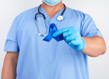 Fototapeta  - doctor in blue uniform and sterile latex gloves holds a dark blue ribbon