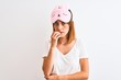 © Krakenimages.com - Beautiful redhead woman wearing sleeping mask over isolated background looking stressed and nervous with hands on mouth biting nails. Anxiety problem.