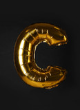 Fototapeta Londyn - Golden letter C balloon on black background