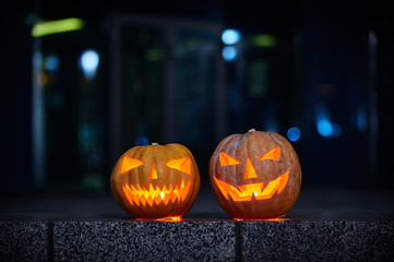 Two glowing Halloween Pumpkins in the city at night. Light the city at night, bokeh.