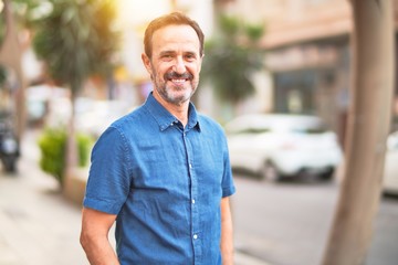 Middle age handsome man standing on the street smiling